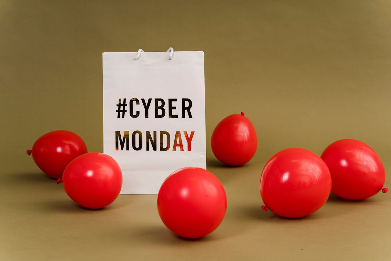 our-values Shopping bag with hashtag Cyber Monday surrounded by vibrant red balloons.